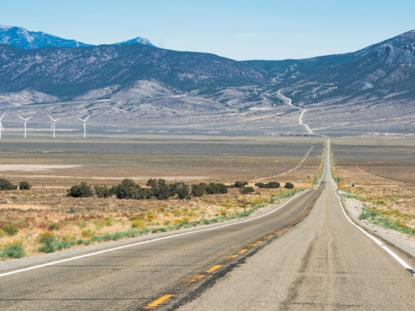 gray concrete road near green grass field and mountains during daytime
